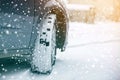 Close up detail car wheel with new black rubber tire protector on winter snow covered road. Transportation and safety concept Royalty Free Stock Photo