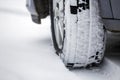 Close up detail car wheel with new black rubber tire protector on winter snow covered road. Transportation and safety concept Royalty Free Stock Photo
