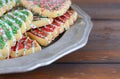 Close up detail of Christmas tree shaped sugar cookies on a pewter plate resting on a rustic wooden table.