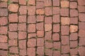 An old road paved with granite stones. Red old brick paving stones background. Royalty Free Stock Photo
