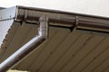 Close-up detail of cottage house corner with brown metal planks siding and roof with steel gutter rain system. Roofing,