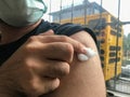 Close up and detail of finger of a man pressing on cotton wool on vaccine shot place on arm after vaccination in hospital room