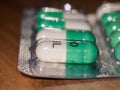 close up detail of foil packet of green and white prozac painkiller tablets on table surface