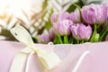 Close-up detail of fresh beautiful present of tender violet peony tulips bouquet and paper gift bag with romantic bow Royalty Free Stock Photo