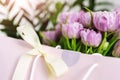 Close-up detail of fresh beautiful present of tender violet peony tulips bouquet and paper gift bag with romantic bow Royalty Free Stock Photo