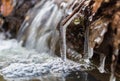 Close up detail of frozen branch in small waterfall, brook. Thawing, weather, early spring background