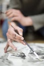 Close up of the detail of the hands of an unrecognizable artist while he is painting with watercolors on a canvas. Art concept