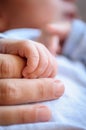 Close-up detail macro view of baby holding on to mom`s finger with his little hand Royalty Free Stock Photo