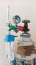 Close-up detail of medical oxygen tank with regulating valve, pressure gauge, flow meter
