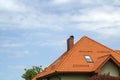 Close-up detail of new modern house top with shingled red roof, high chimney, attic windows on clear blue sky copy space backgroun Royalty Free Stock Photo