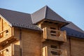 Close-up detail of new modern wooden warm ecological cottage house top with shingled brown roof and wooden sidings on blue sky Royalty Free Stock Photo