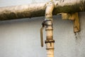 Close-up detail of old dirty painted yellow natural gas pipes with welding seams and faucet valve fastened to gray house wall. Saf Royalty Free Stock Photo