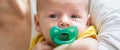 Close-up detail portrait of mother in her hands holding cute little peaceful newborn baby with pacifier in his mouth Royalty Free Stock Photo