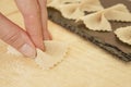 Close up detail of process of homemade vegan farfalle pasta with durum wheat flour. The cook kneads the dough on the wooden Royalty Free Stock Photo