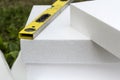 Close-up detail of stack of white rigid polyurethane foam sheets for house insulation and level. Modern technology, renovation, pr