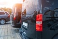 Close-up detail tail light view of many modern luxury black vans parked in row at car sale rental leasing dealer against
