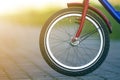 Close-up detail of teenager bicycle front wheel on gray pavement blurred bokeh background on bright sunny day. Urban comfortable Royalty Free Stock Photo