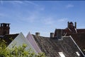 Close up detail of town house rooftops with chimneys against blue sky. Royalty Free Stock Photo