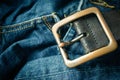 close up detail of an unbuckled leather belt on a faded pair of blue jeans Royalty Free Stock Photo