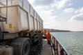 Close-up detail view of big industrial hopper truck body loaded on cargo ferry boat sailing on river or sea port blue Royalty Free Stock Photo