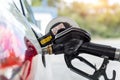 Close-up detail view of black pistol handle inserted in white diesel car fuel tank refueling at petrol refueling station