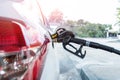 Close-up detail view of black pistol handle inserted in white diesel car fuel tank refueling at petrol refueling station