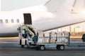 Close-up detail view of cargo cart trolley full with commercial parcels against turboprop cargo plane. Air mail shipping