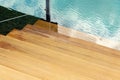 Close-up detail view of natural wooden stair steps of larch ladder into clean blue water of lake, sea or pond. Waterpoof