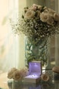 Close-up detail of wedding rings by the window with blowing curtains and slippers and a white flower arrangement on a glass table Royalty Free Stock Photo