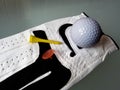 Close-up detail of golf glove golf ball and yellow tee Royalty Free Stock Photo