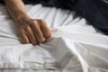 Close up detail of a womens hand grabbing on to the bed sheets, intimacy, erotic concept