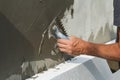Close-up of detail of worker hand with trowel applying glue on plastered white house wall doing insulation with polyurethane foam. Royalty Free Stock Photo
