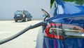 CLOSE UP: Detailed shot of a shiny new Tesla car recharging at a parking lot. Royalty Free Stock Photo