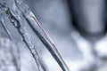 Close up detailed view on few transparent melting thin icicles in spring with very blurry snowy roof, blue tone. Very sharp piece