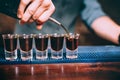 Close up details of bartender pouring alcoholic drink in small glasses at anniversary party