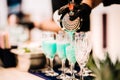 Close up details of bartenders tools and hand while pouring exotic tropical blue curacao cocktail into glasses Royalty Free Stock Photo