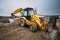 Close up details of massive working machinery, industrial backhoe loader with excavator on construction site