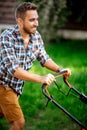 Close up details and portrait of gardener using industrial manual lawnmower