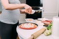 Close up details of pregnant woman making home pizza