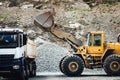 Close up details of wheel loader with scoop working on construction site and loading gravel Royalty Free Stock Photo