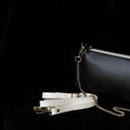 Close-up detal of leather handbag, always classic combination, black and white color with strap and chain. For modern