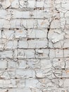 Close-up of a deteriorating white brick wall, showcasing peeling paint that reveals the rough texture beneath. Royalty Free Stock Photo