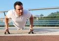 Close-up of a determined handsome middle aged man, athlete exercising outdoor, pumping muscles while performing push-ups training