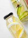 Close up of detox drinks lemon and lime in glass bottles on white background. Macro photography with focus on the Royalty Free Stock Photo