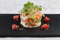 Close-up Diced salmon salad with avocado, tomato, onion, chilli, and coriander served in black rectangle stone plate on washi.