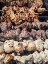 Close up of different kinds of meat on metal skewers - pork and chicken grilling on fire, coals and smoke in grill. Macro of Royalty Free Stock Photo