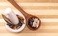 Close-up of different spices in white mortar pestle and ayurvedic medicines in a wood spoon on chopping board background
