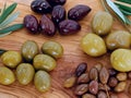 Close up of different types of olives on a wooden serving plate, mixed olives of different sizes as a healthy appetizer Royalty Free Stock Photo