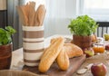 Close-up on dining table with baguettes, basil, apples and container with wooden spoons Royalty Free Stock Photo