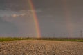 close up from a dirt road with many stones and a double rainbow at the end Royalty Free Stock Photo